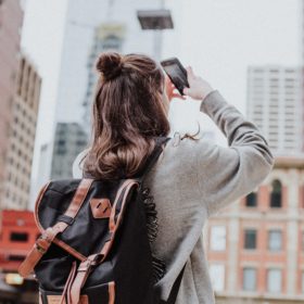 woman taking photo of high-rise building beside road